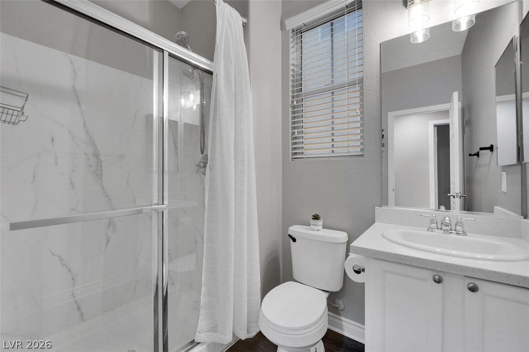 An elegant bathroom features a glass-enclosed shower alongside a classic white vanity.
