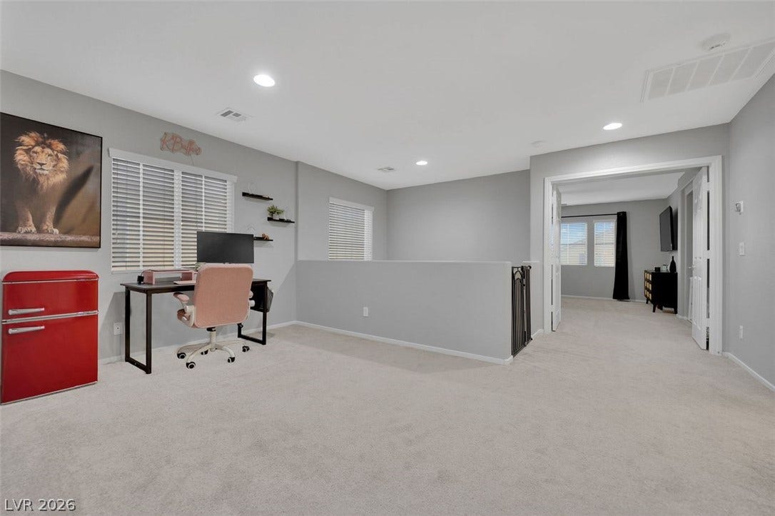 Plentiful recessed lighting illuminates a versatile upper-level loft with soft carpeting.