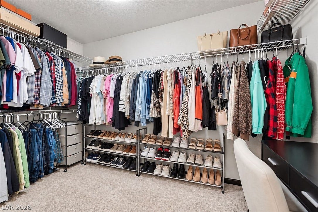 A spacious walk-in closet includes wall-to-wall carpeting and multiple rows of wire shelving.