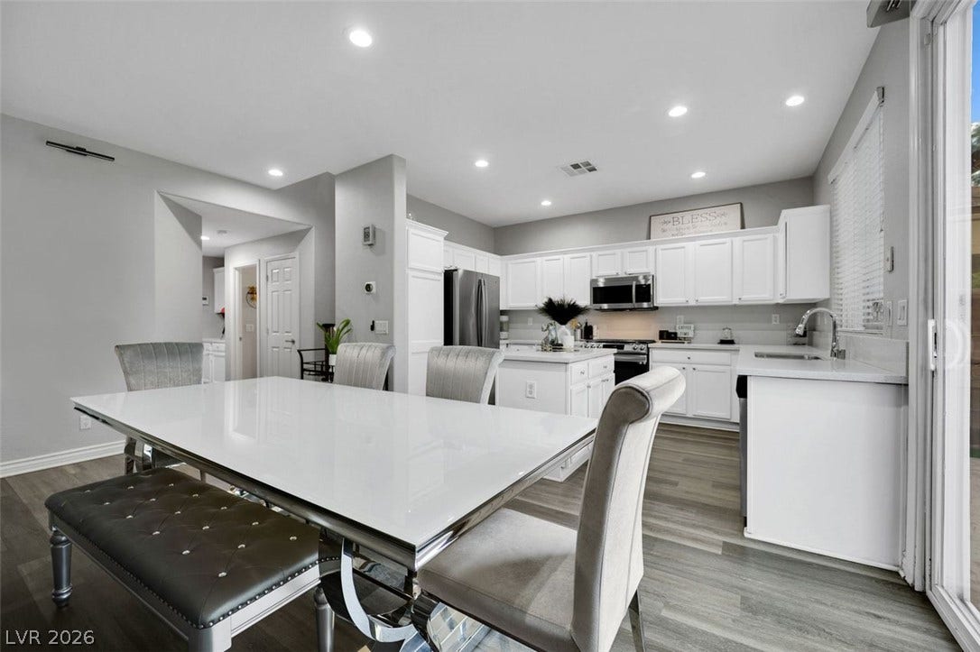 Recessed lighting illuminates this seamless transition between a modern kitchen and adjacent dining area.