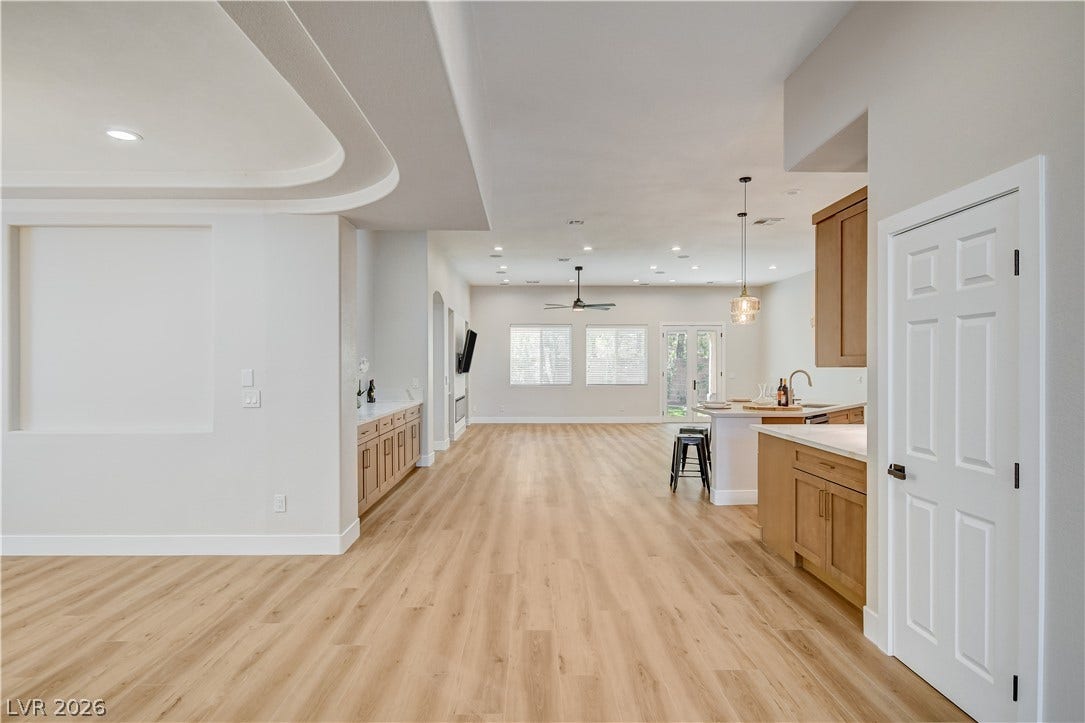 Warm wood flooring stretches through a spacious open layout illuminated by subtle recessed lighting.