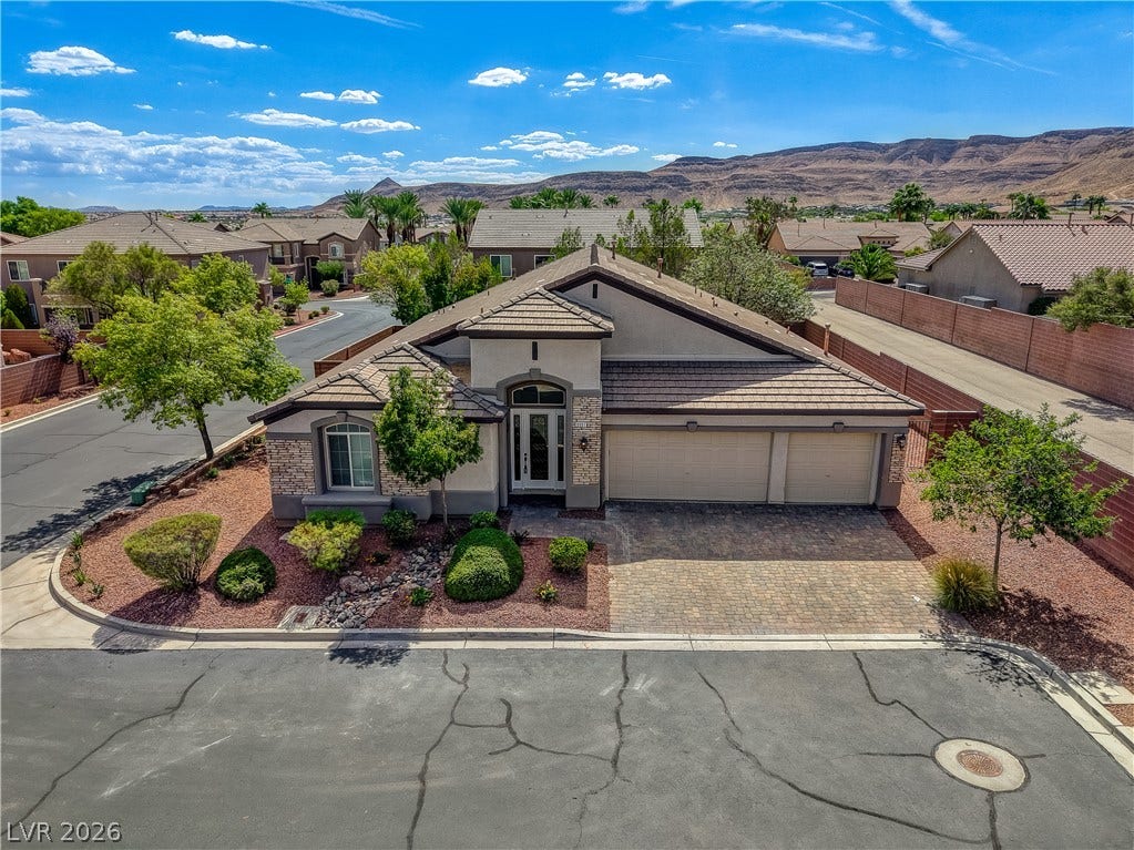 Desert landscaping and a paved driveway complement this elegant tile-roof home set against scenic hills.