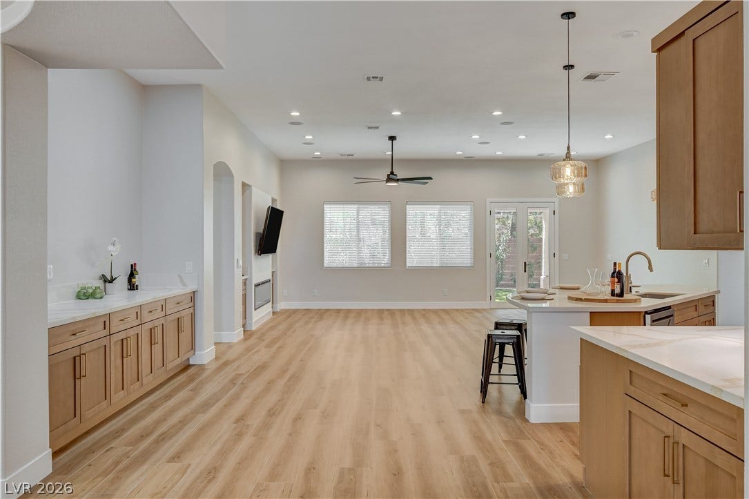 An open floor plan connects the kitchen and living areas over seamless wood-style flooring.
