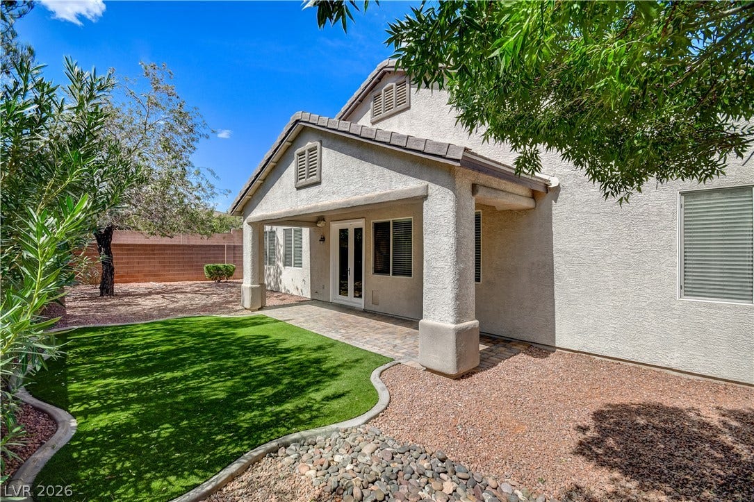 A shaded patio opens to a manicured lawn and low-maintenance desert landscaping.