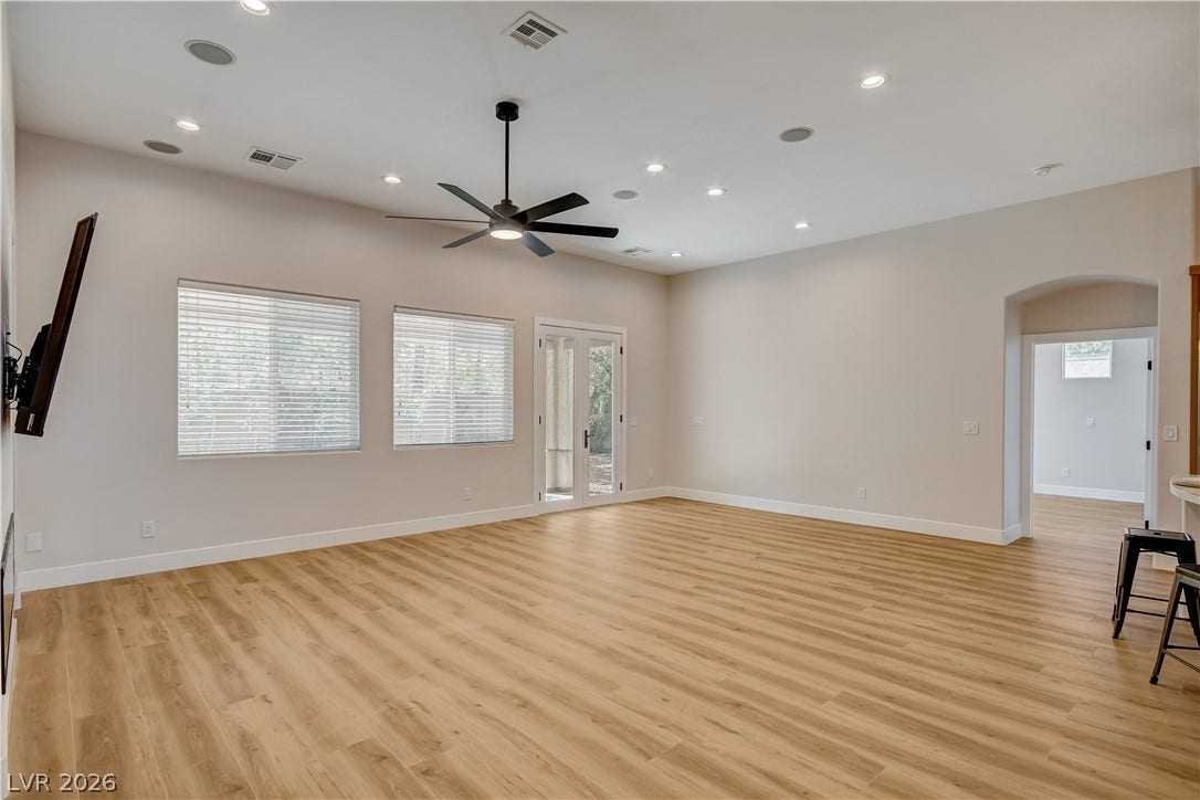 Recessed lighting illuminates this airy living space complete with handsome wood-look flooring.