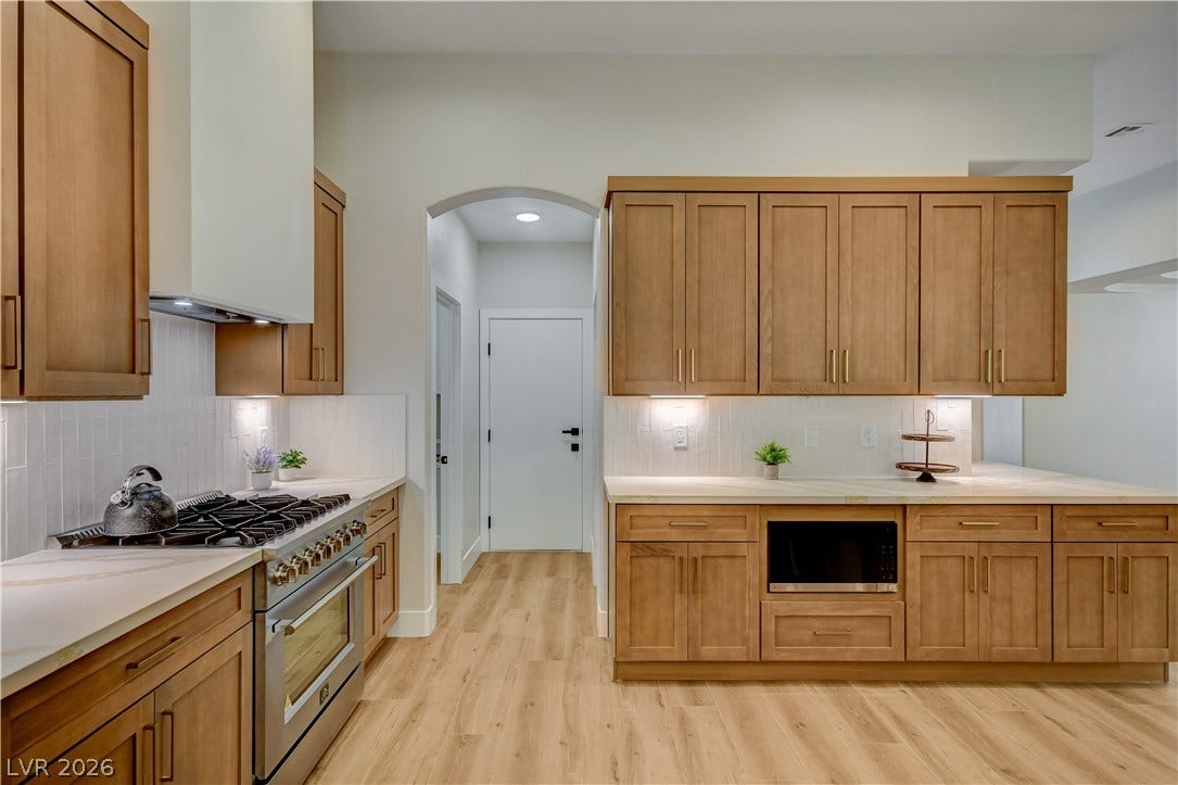 Warm wood cabinetry and clean stone countertops define this modern kitchen workspace.
