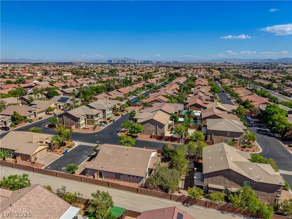 An aerial perspective showcases a neat residential neighborhood framed by mountain and distant city views.