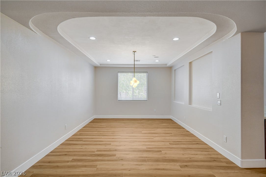 A unique recessed ceiling detail highlights this spacious dining area with wood-look flooring.