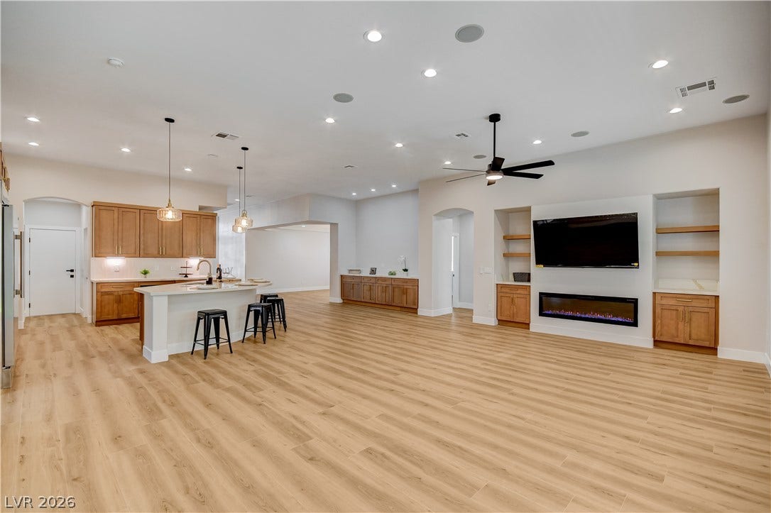 A spacious layout seamlessly connects the kitchen and living area over warm wood flooring.