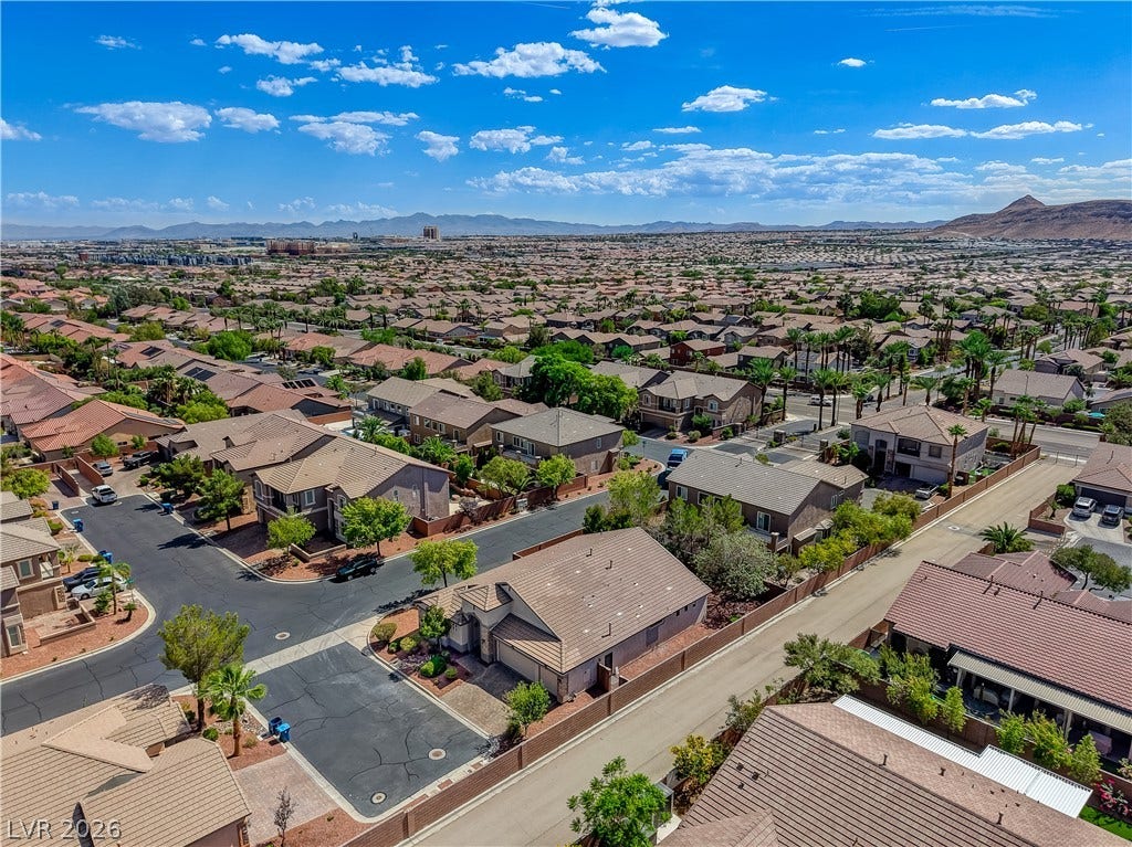 A sweeping aerial view showcases the sprawling suburban neighborhood nestled against a distant mountain backdrop.