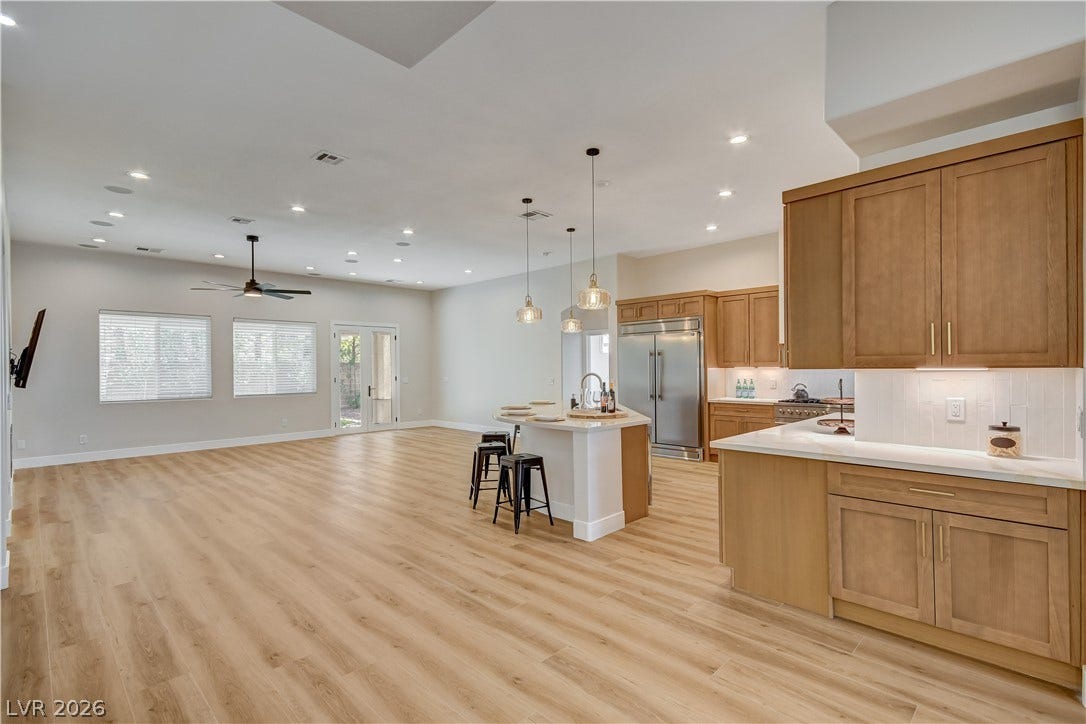 A spacious open-plan kitchen and living area is highlighted by natural wood cabinetry and matching floors.