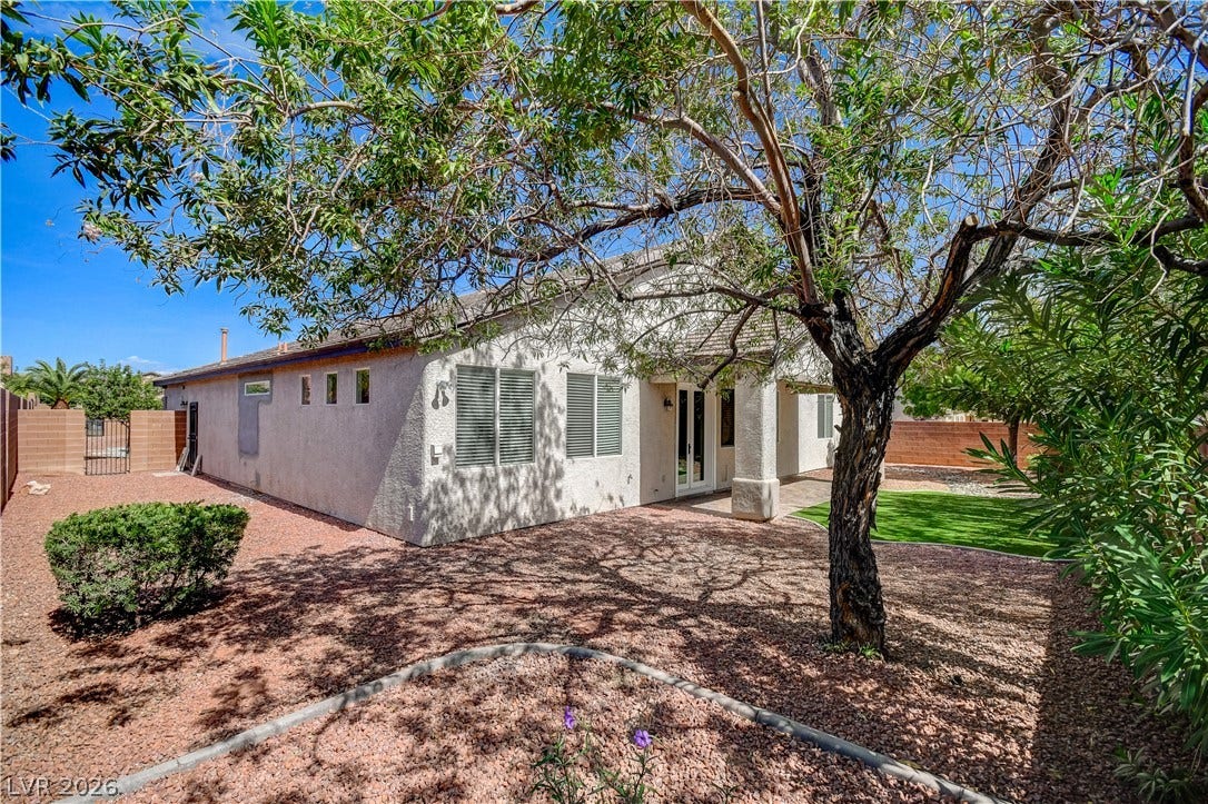 Mature trees shade the low-maintenance gravel landscaping of this private backyard sanctuary.