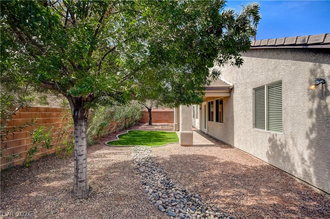 Mature trees shade a low-maintenance gravel yard complete with a synthetic turf putting green.