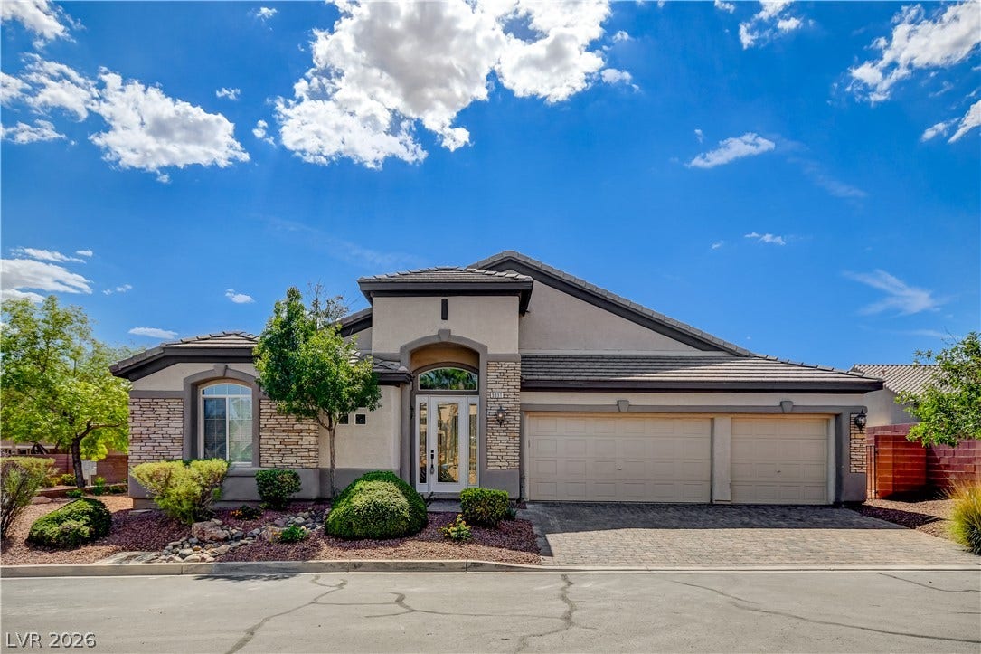Stately stone accents and a spacious three-car garage define this elegant single-story facade.