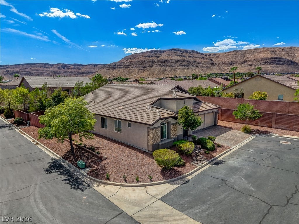 Dramatic mountain backdrops frame this corner lot home featuring a tiled roof and stone accents.