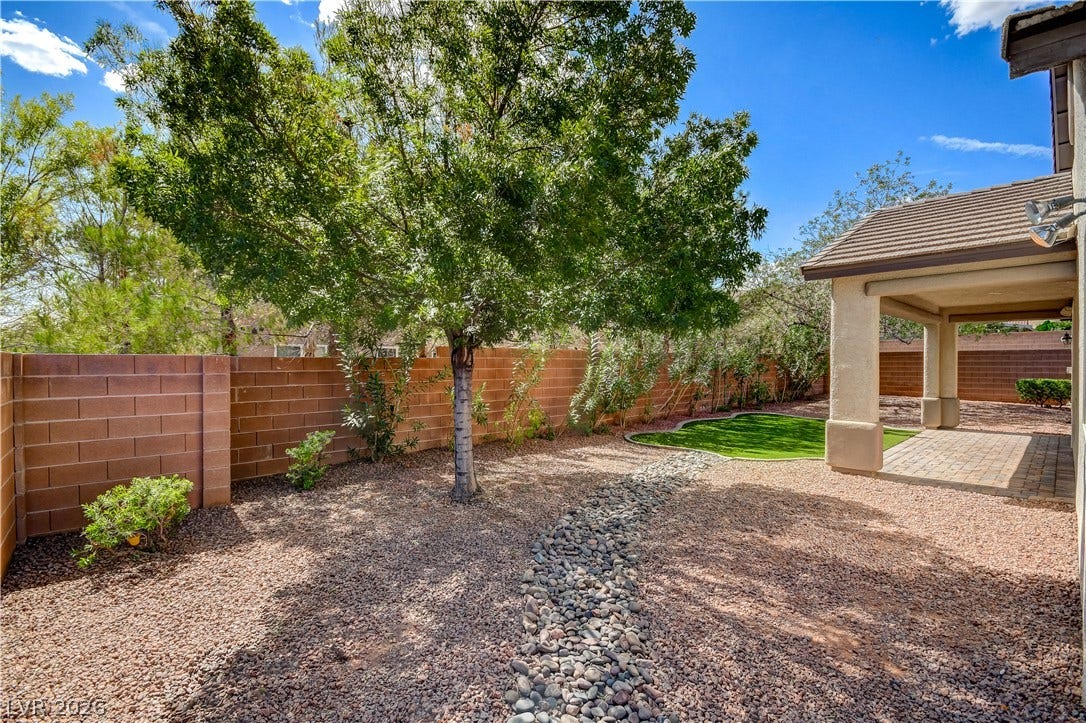 Mature trees and a gravel pathway enhance the private walled yard.