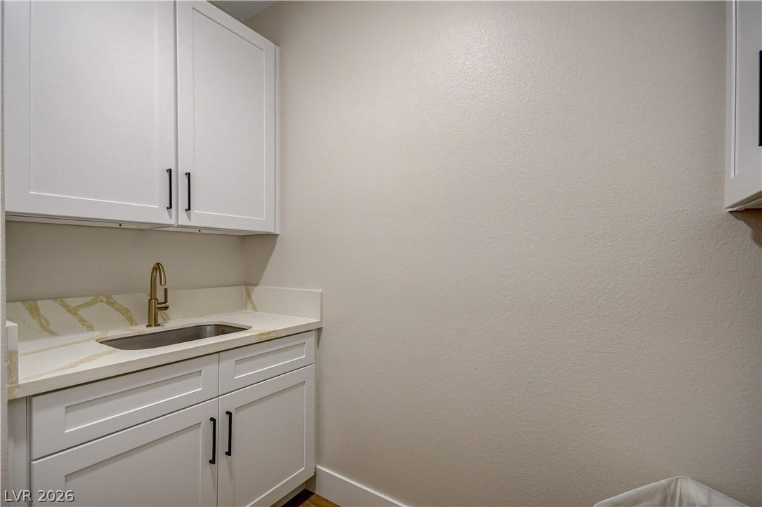 White shaker cabinetry and quartz countertops frame a convenient utility sink area.