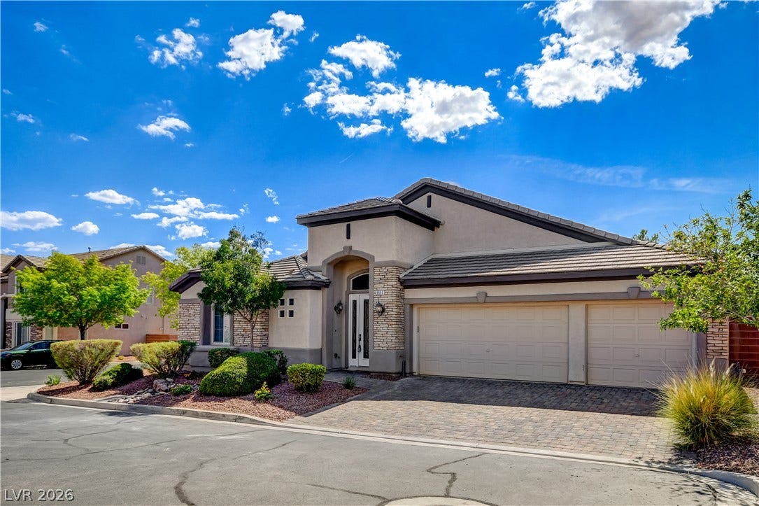Stone accents and a paved driveway enhance the striking exterior of this single-story home.