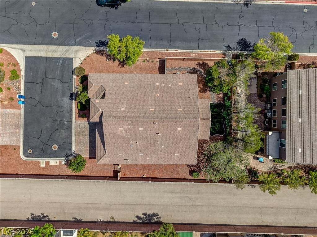 An overhead perspective reveals the home's layout, shingle roof, and surrounding hardscape elements.