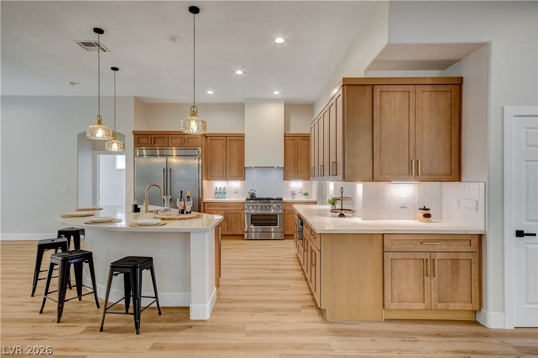 Warm wood cabinetry and light stone countertops anchor this modern, light-filled kitchen space.