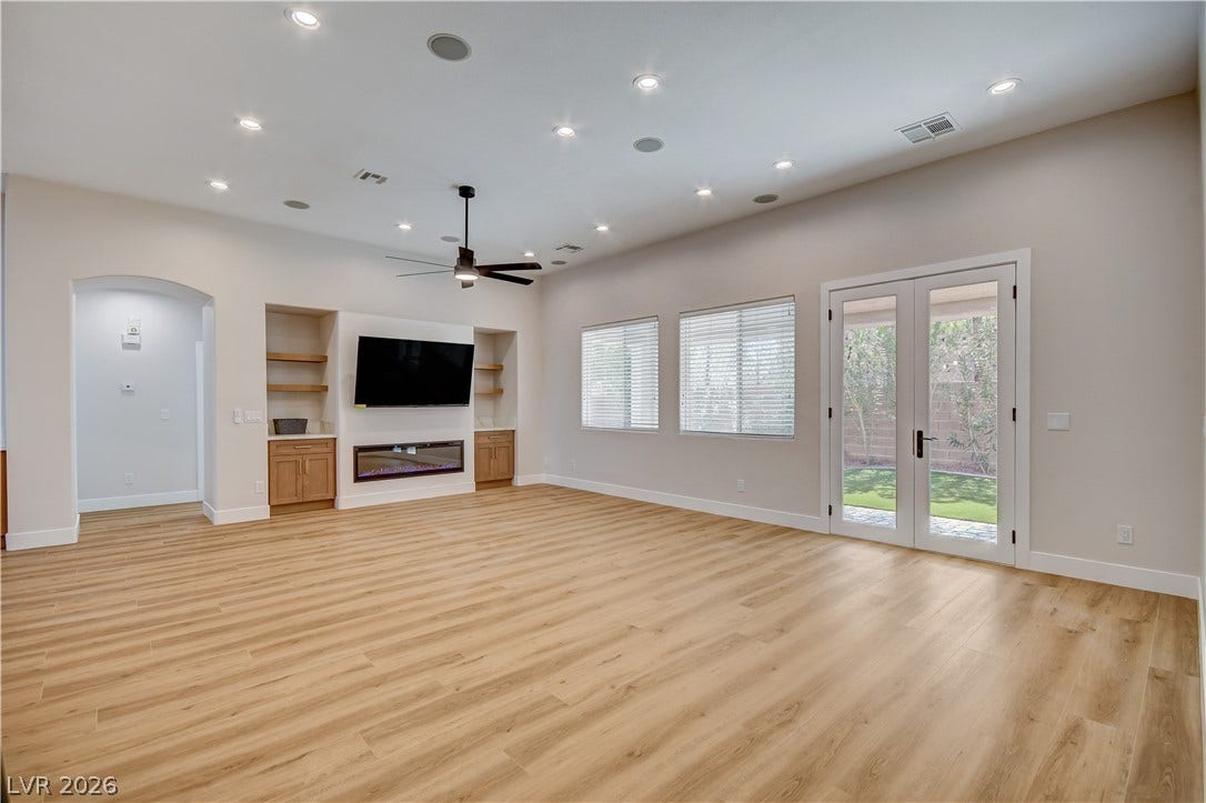 Warm wood flooring and built-in shelving anchor this airy living space with French doors.