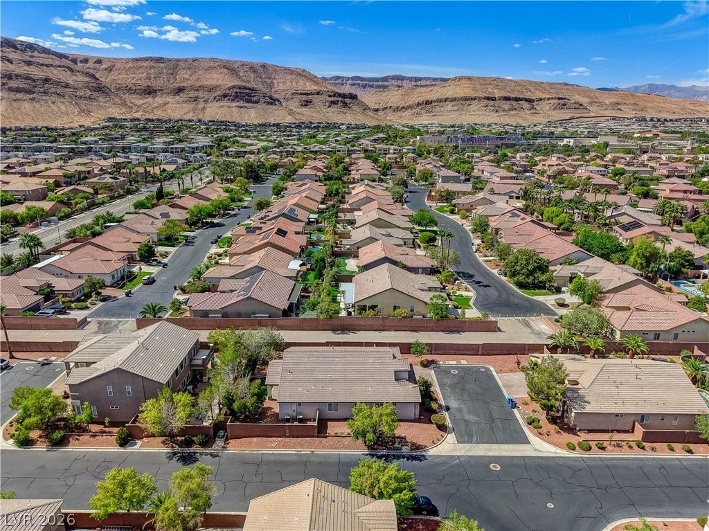 Dramatic mountain backdrops frame this peaceful residential neighborhood under clear blue skies.