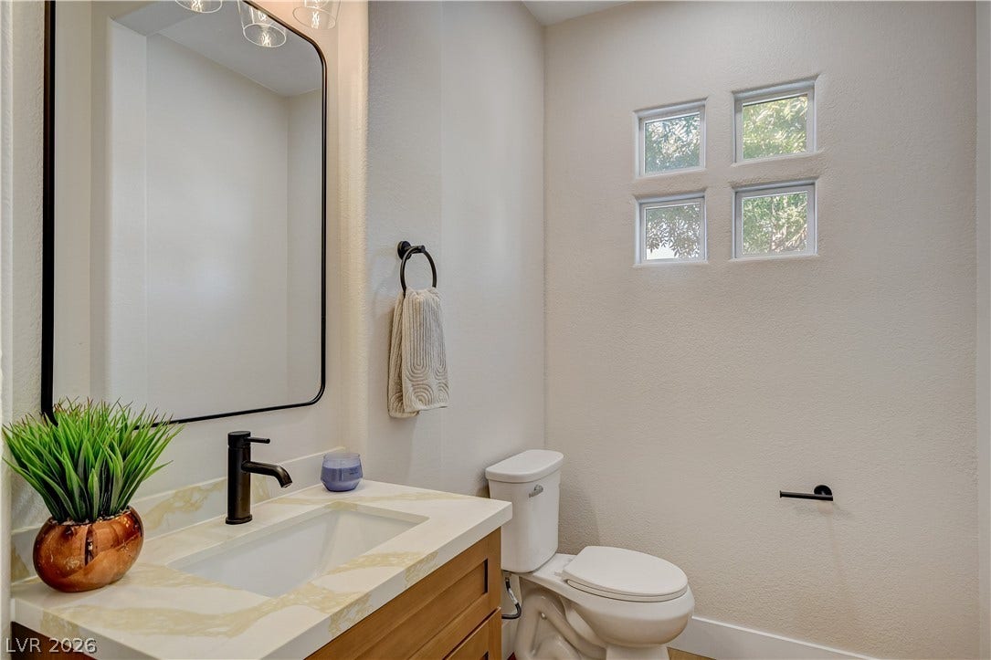 High ceilings and a stone counter vanity define this stylish, functional powder room.