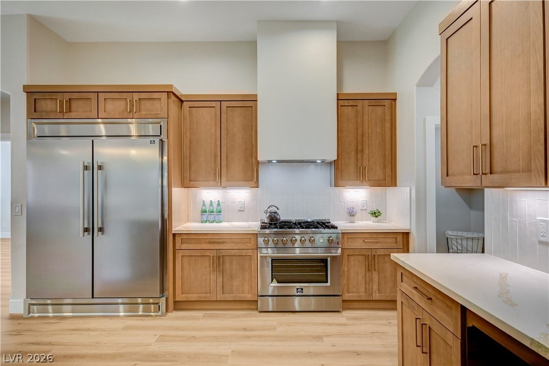 Warm wood cabinetry pairs with professional stainless appliances and sleek quartz countertops.