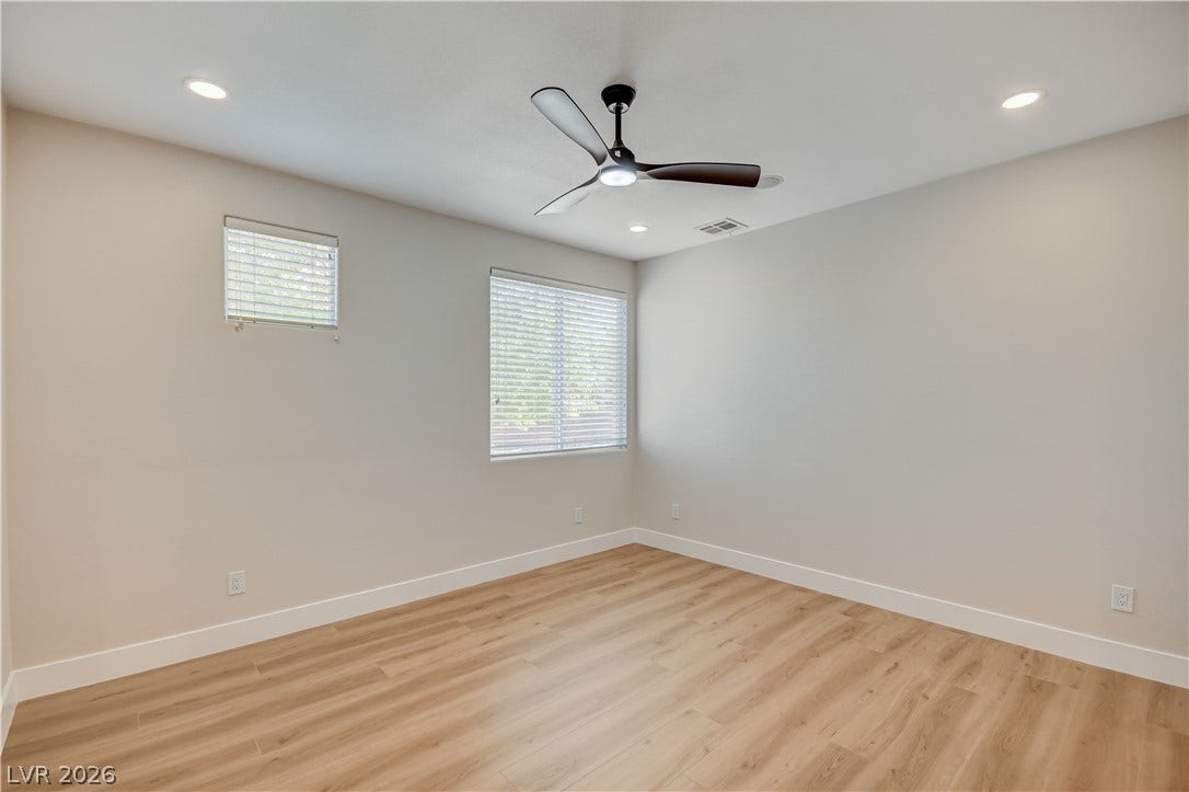 Smooth wood-style flooring and recessed lighting define this versatile, neutral interior space.