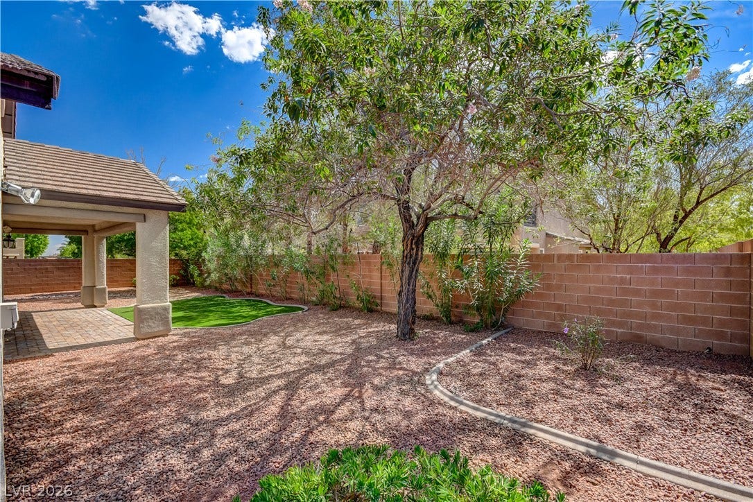 A spacious backyard features a covered patio, low-maintenance landscaping, and mature shade trees.