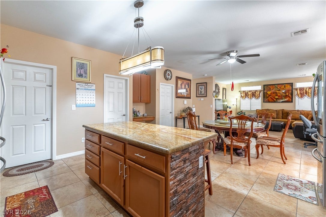 An open floorplan seamlessly connects the stone-countertop kitchen island to the adjacent dining area.