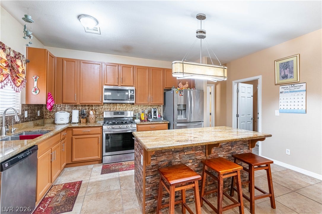 Warm wooden cabinetry and a stone-accented island anchor this kitchen with tile flooring.