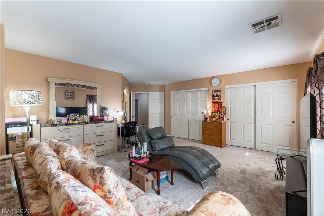 A spacious bedroom features neutral walls, wall-to-wall carpeting, and multiple closets.