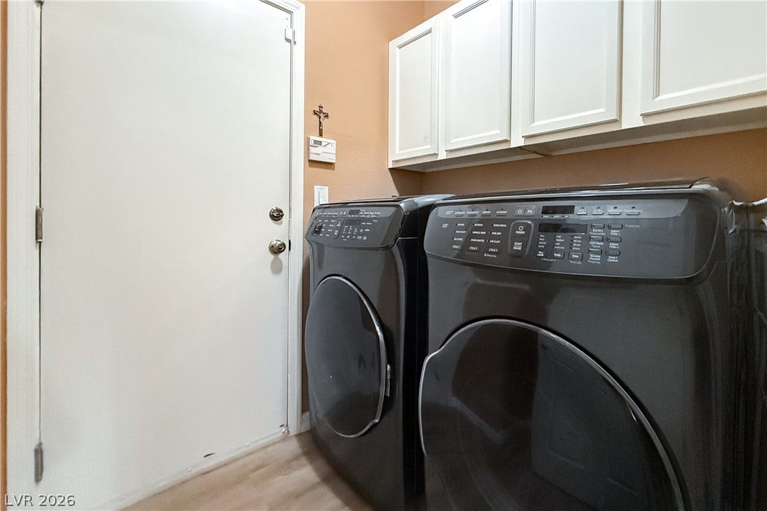 Ample upper cabinetry and durable hard surface flooring optimize this functional laundry workspace.