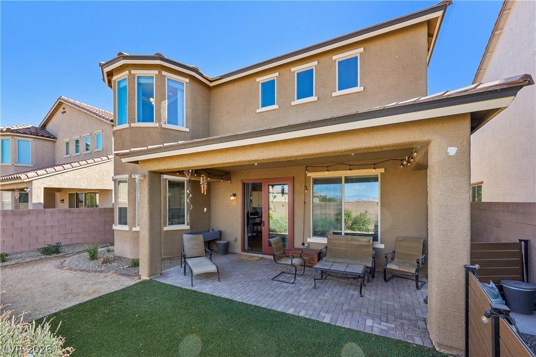 9490 Wild Valley Avenue, Las Vegas, NV 89148 A covered patio with brick pavers extends directly to a low-maintenance lawn.