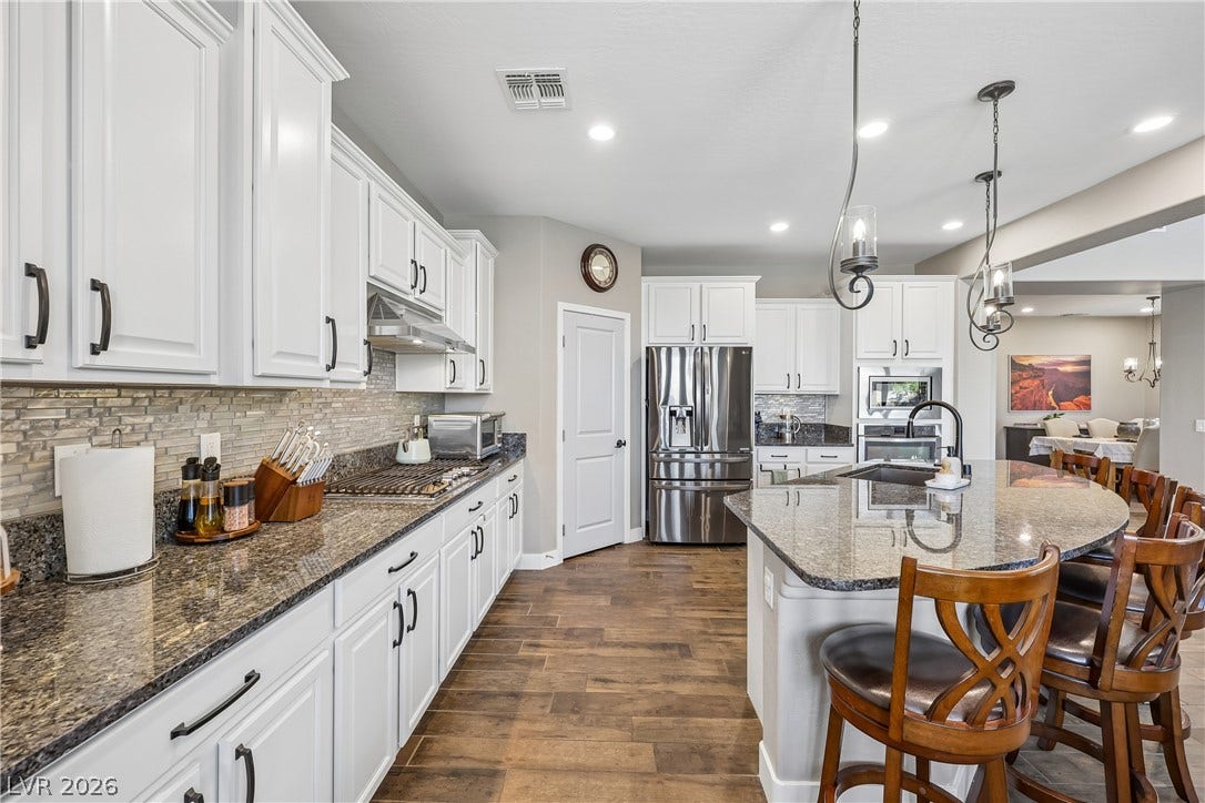 9490 Wild Valley Avenue, Las Vegas, NV 89148 Polished granite countertops complement classic white cabinetry and durable wood-look flooring.