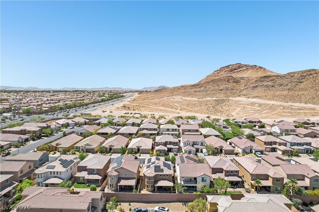 9490 Wild Valley Avenue, Las Vegas, NV 89148 Dramatic mountain slopes rise directly behind this residential community under a clear blue sky.