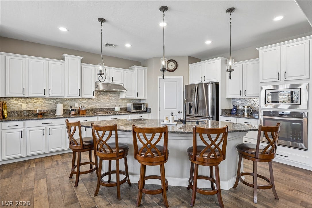 9490 Wild Valley Avenue, Las Vegas, NV 89148 Rich wood floors complement pristine cabinetry and stone countertops in this modern gourmet space.