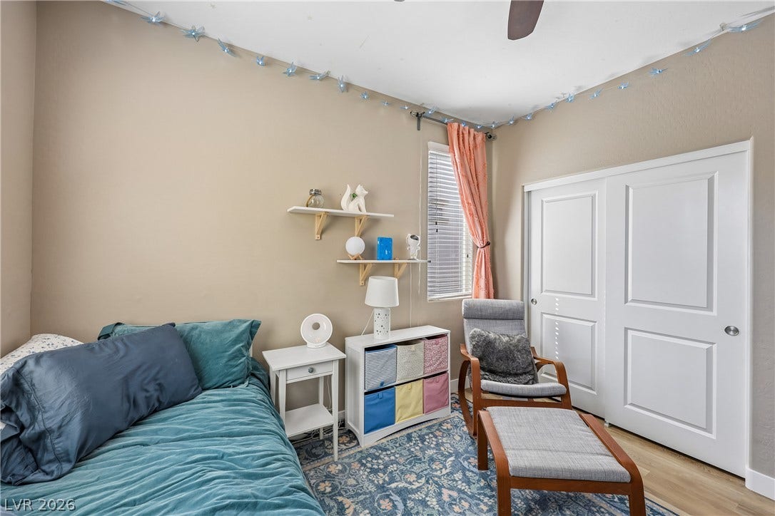 9490 Wild Valley Avenue, Las Vegas, NV 89148 Natural light streams through the window of this cozy bedroom with wood-style flooring.