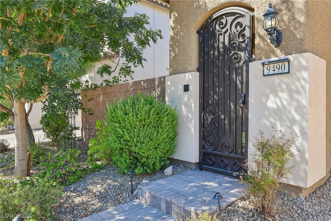 9490 Wild Valley Avenue, Las Vegas, NV 89148 An arched wrought-iron gate secures the private entryway of this stucco home.