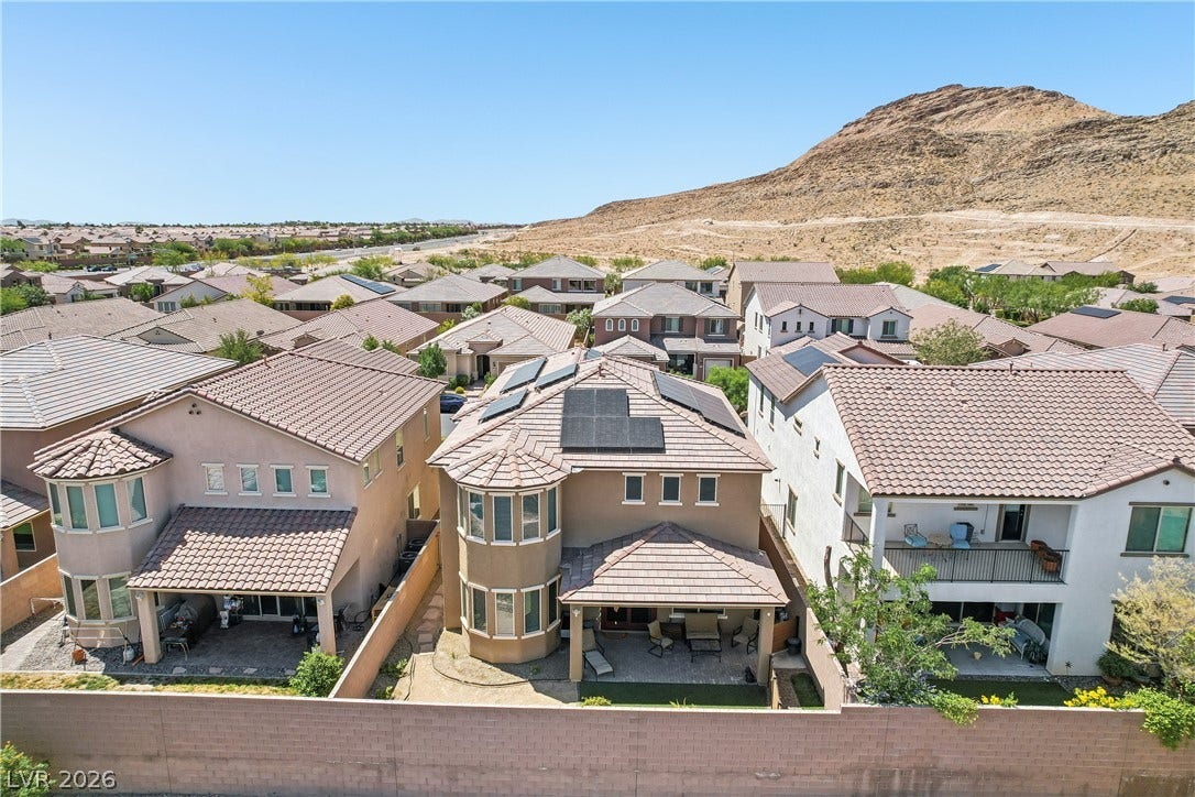9490 Wild Valley Avenue, Las Vegas, NV 89148 An aerial view showcases modern multi-level homes nestled near a desert hillside.
