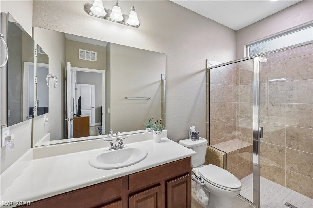 9490 Wild Valley Avenue, Las Vegas, NV 89148 A glass-enclosed walk-in shower with tile accents sits adjacent to a spacious single-sink vanity.