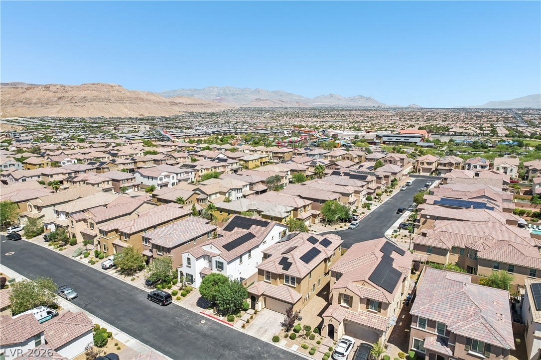 9490 Wild Valley Avenue, Las Vegas, NV 89148 An elevated perspective showcases the surrounding neighborhood houses set against a mountainous desert backdrop.