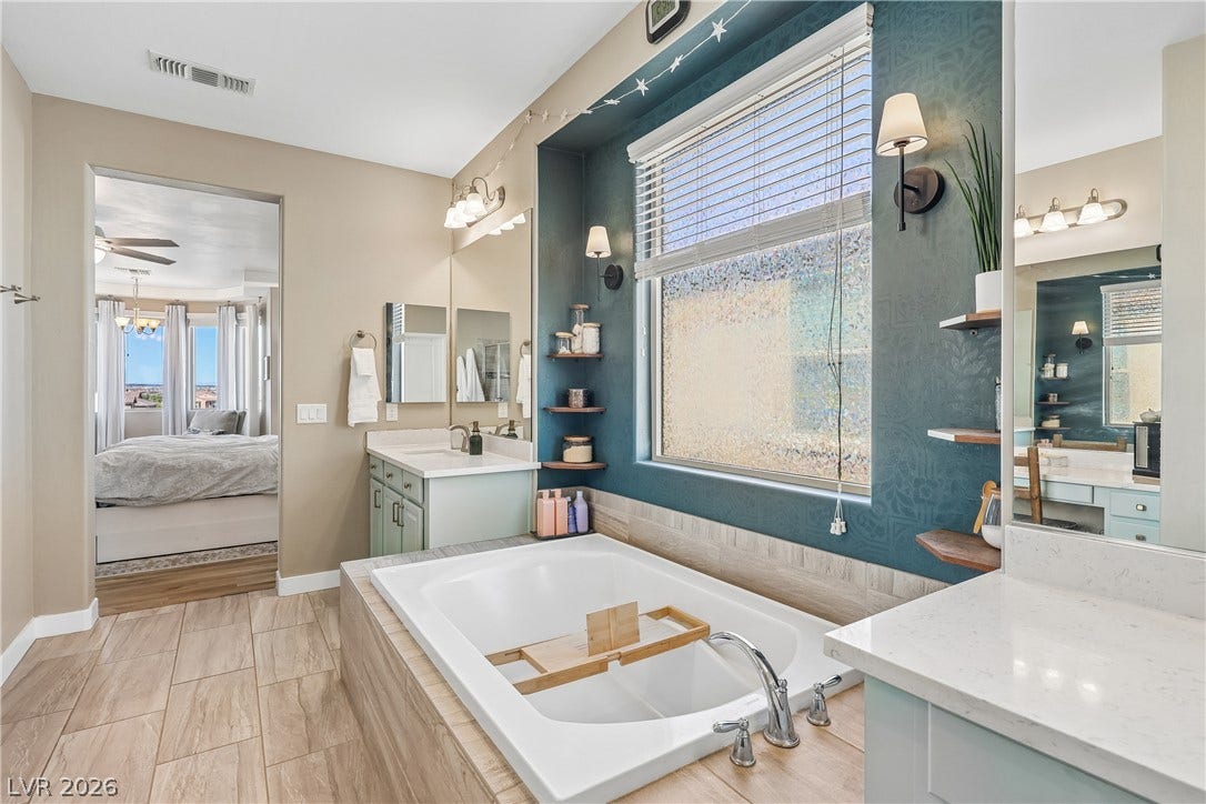 9490 Wild Valley Avenue, Las Vegas, NV 89148 An inviting soaking tub pairs with tile flooring and dual vanities in this bathroom.