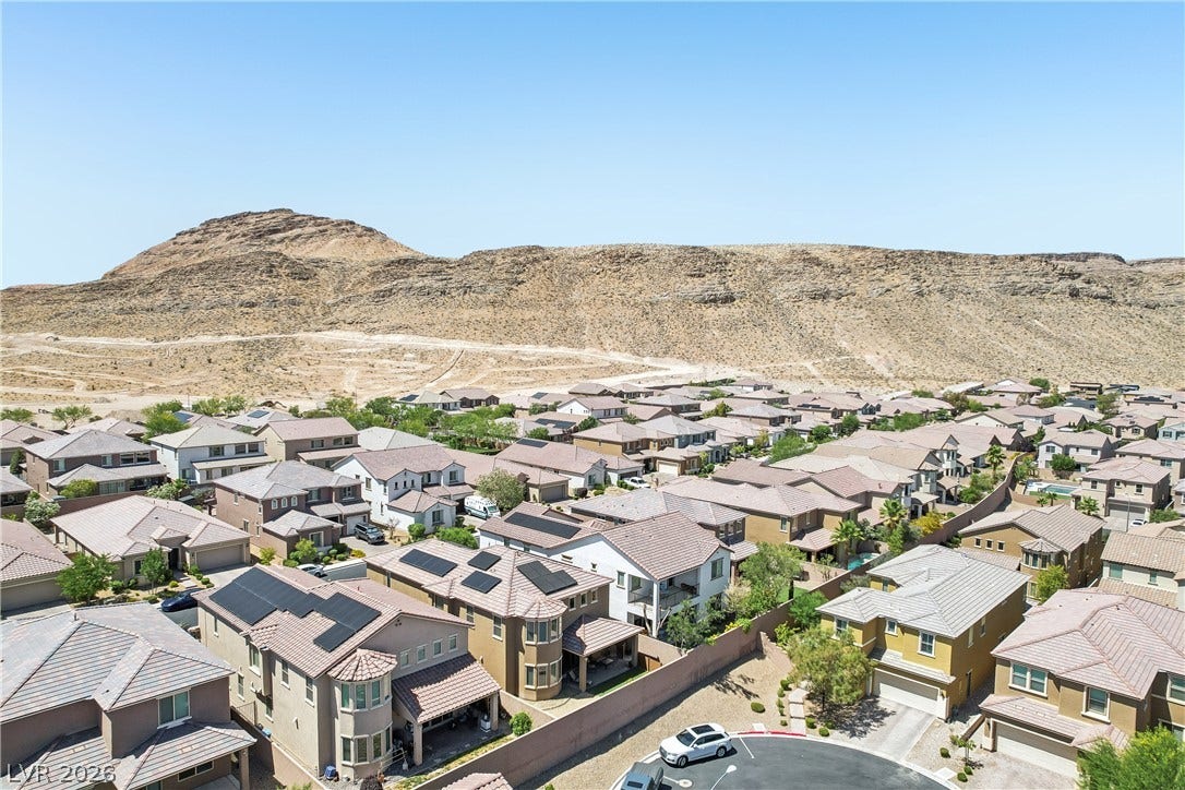 9490 Wild Valley Avenue, Las Vegas, NV 89148 An aerial view showcases a peaceful residential neighborhood set against a desert mountain backdrop.