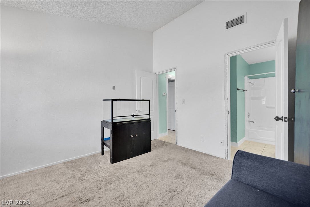 Vaulted ceilings soar over plush carpeting, leading directly into an attached private bathroom.