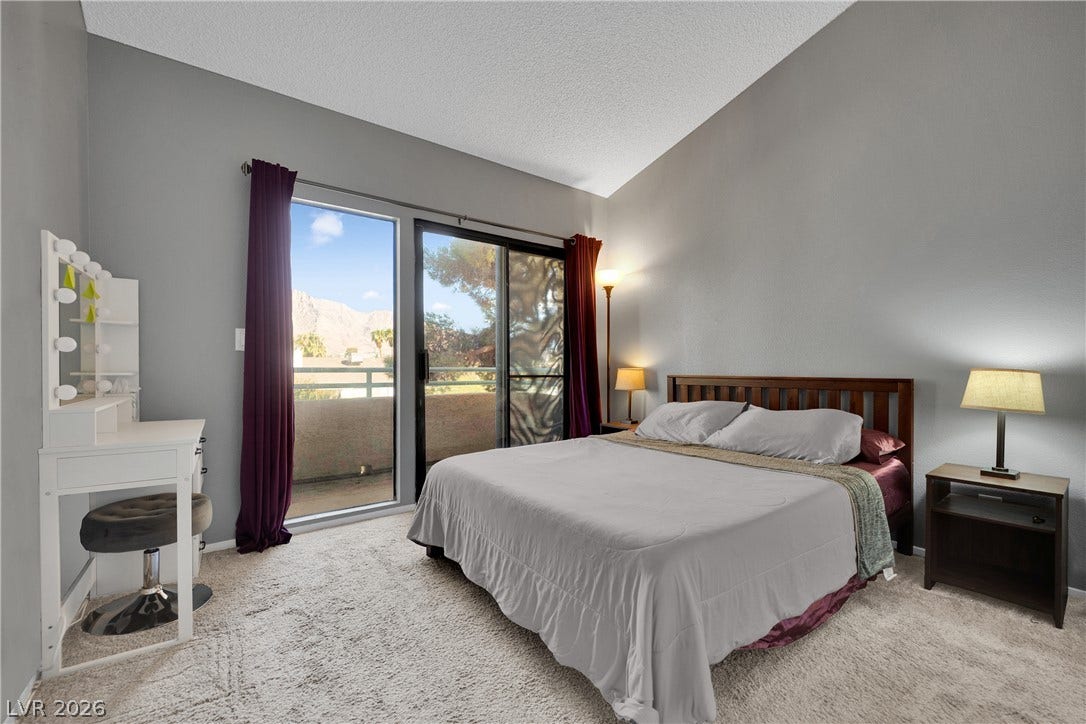 High vaulted ceilings and glass sliding doors lead out to a private balcony space.
