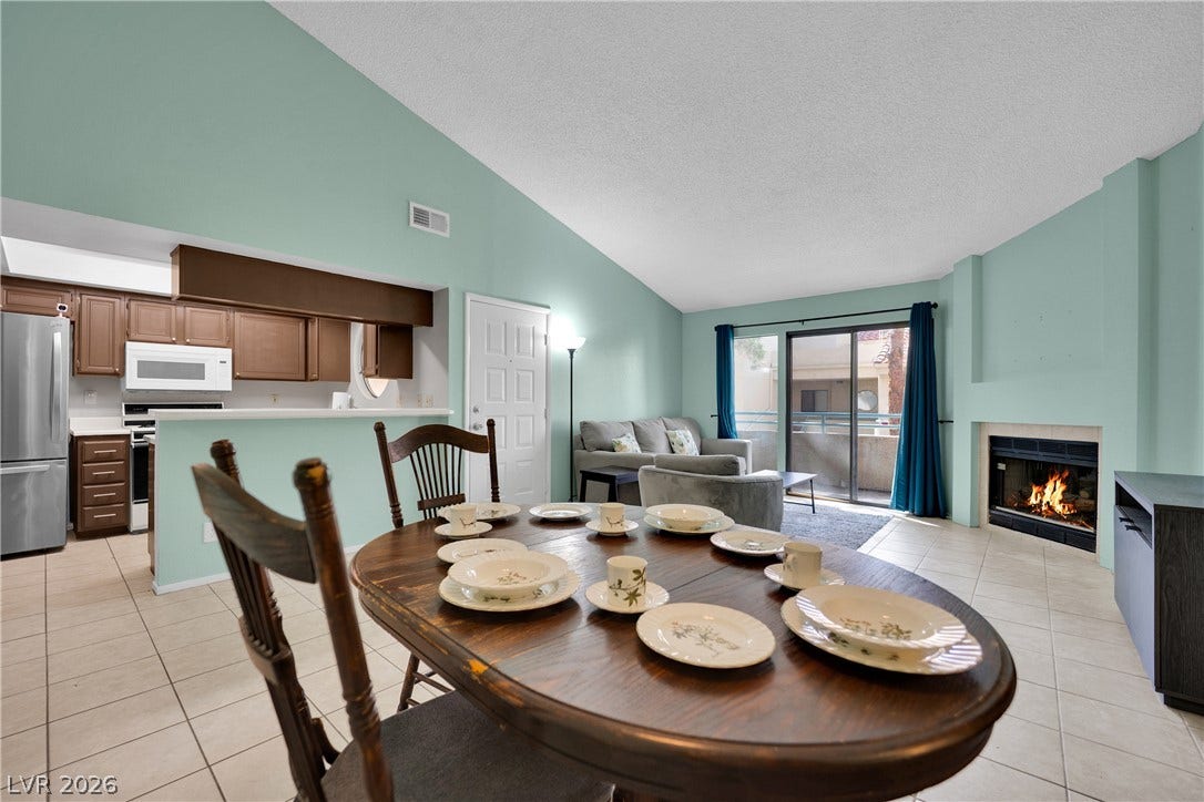 High vaulted ceilings and a cozy fireplace highlight this open concept dining and living space.