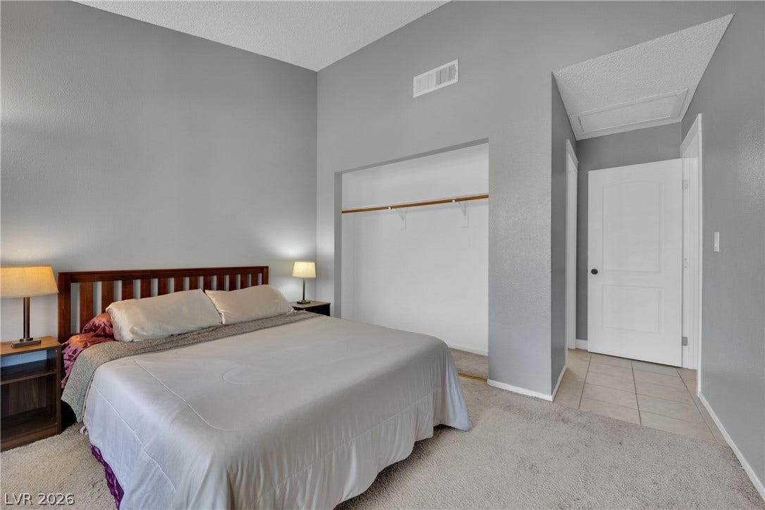 Vaulted ceilings elevate this serene bedroom featuring carpet floors and a spacious built-in closet alcove.