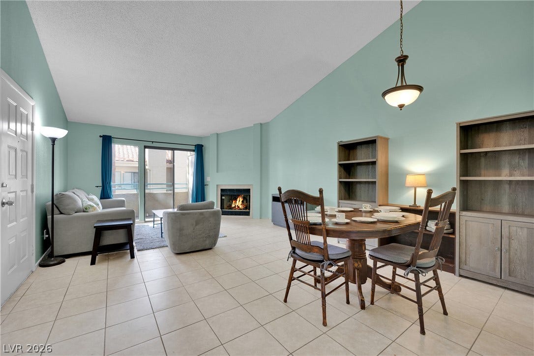 Soaring vaulted ceilings and tile flooring enhance this open-concept dining and living area with a fireplace.